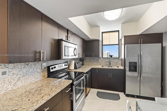 18181 NE 31st Ct Unit Ph07, Aventura, FL 33160 - kitchen with stainless steel appliances, a sink, decorative backsplash, dark brown cabinets, and light stone countertops