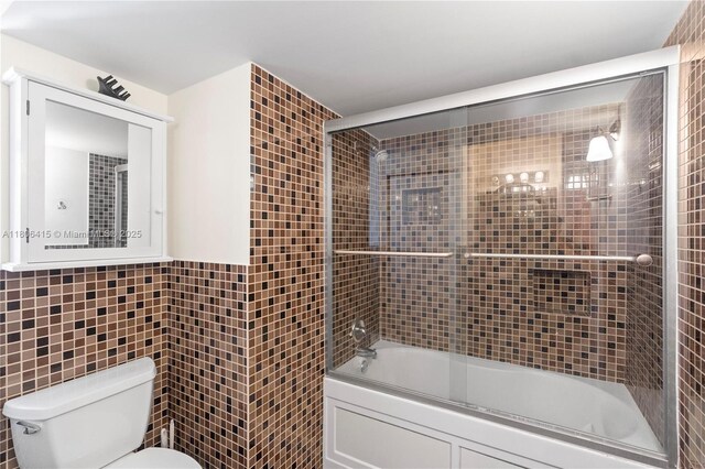 18181 NE 31st Ct Unit Ph07, Aventura, FL 33160 - full bath featuring tile walls, toilet, and shower / bath combination with glass door