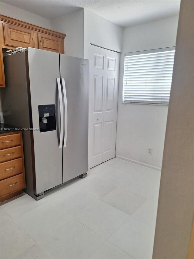 6621 Winfield Blvd Unit 1, Margate, FL 33063 - kitchen with stainless steel fridge with ice dispenser, brown cabinetry, light tile patterned flooring, and dark countertops