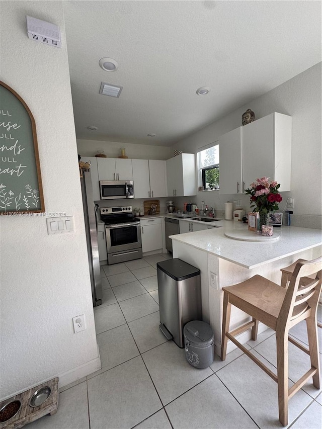 28577 SW 134th Ct, Homestead, FL 33033 - kitchen featuring stainless steel appliances, white cabinetry, light countertops, a peninsula, and a sink