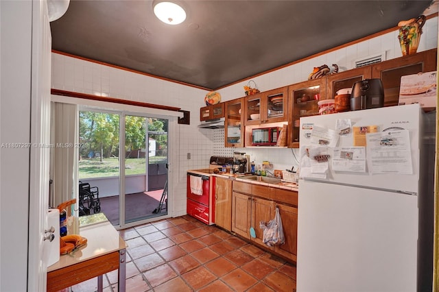 45 NW 127th St, North Miami, FL 33168 - kitchen with freestanding refrigerator, electric range, brown cabinets, light countertops, and under cabinet range hood