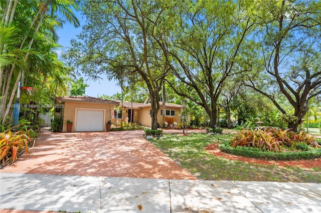 1090 Meadowlark Ave, Miami Springs, FL 33166 - view of front of home with decorative driveway, stucco siding, a garage, and a tile roof