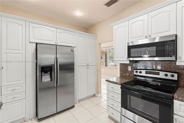 1090 Meadowlark Ave, Miami Springs, FL 33166 - kitchen featuring stainless steel appliances, white cabinets, light tile patterned floors, backsplash, and dark stone countertops