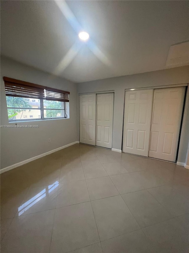 7368 SW 82nd St Unit E215, Miami, FL 33143 - unfurnished bedroom featuring two closets, baseboards, and tile patterned floors