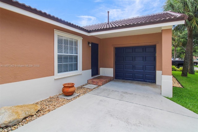 19171 NW 89th Ct, Hialeah, FL 33018 - view of exterior entry with a tiled roof, concrete driveway, a garage, and stucco siding