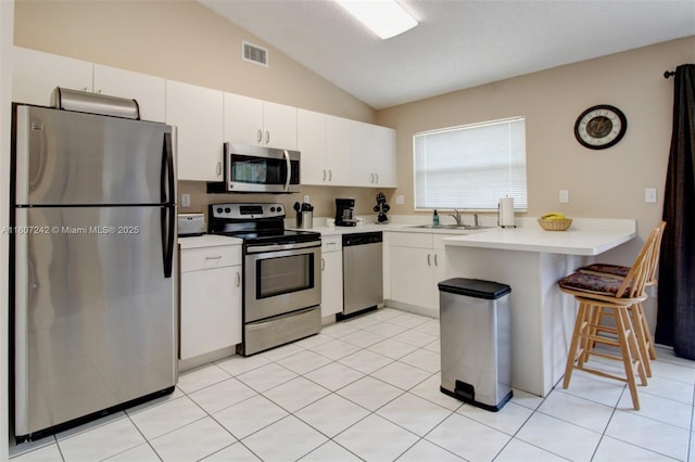 19171 NW 89th Ct, Hialeah, FL 33018 - kitchen with appliances with stainless steel finishes, a peninsula, vaulted ceiling, light countertops, and white cabinets