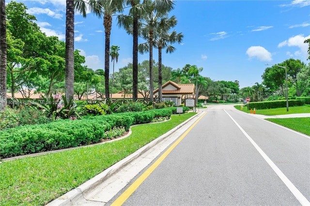 6080 Huntwick Ter Unit 202, Delray Beach, FL 33484 - view of asphalt road with traffic signs, street lighting, view of wooded area, and curbs
