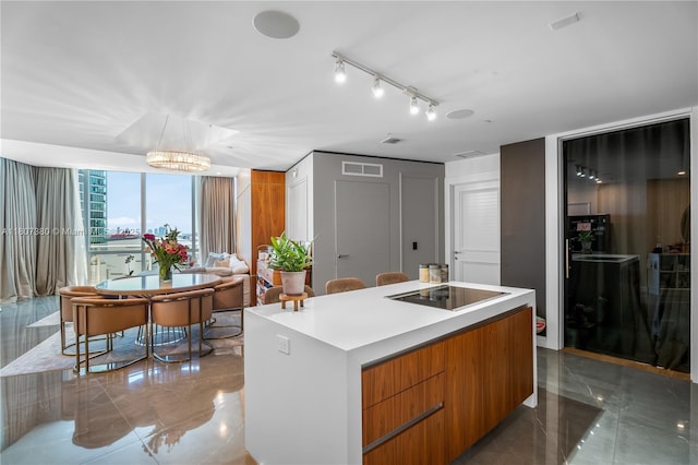 851 NE 1st Ave Unit 1409, Miami, FL 33132 - kitchen with black electric stovetop, modern cabinets, a kitchen island, brown cabinets, and light countertops