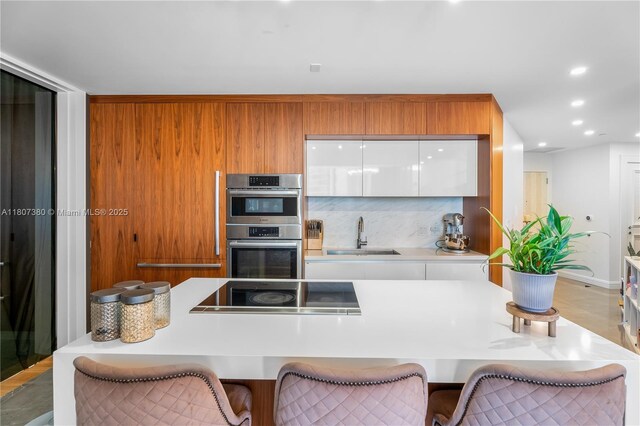 851 NE 1st Ave Unit 1409, Miami, FL 33132 - kitchen featuring a sink, modern cabinets, black electric cooktop, stainless steel double oven, and white cabinetry