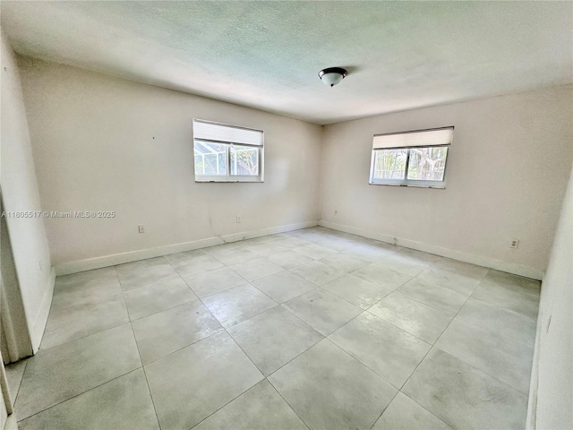 8890 SW 155th Ter, Palmetto Bay, FL 33157 - unfurnished room featuring plenty of natural light, baseboards, a textured ceiling, and light tile patterned floors
