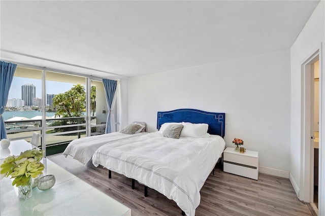 900 Bay Dr Unit 210, Miami Beach, FL 33141 - bedroom with wood finished floors, access to exterior, baseboards, and a city view