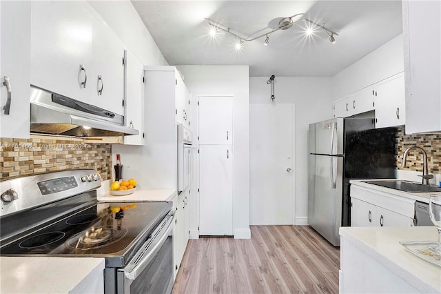 900 Bay Dr Unit 210, Miami Beach, FL 33141 - kitchen featuring appliances with stainless steel finishes, under cabinet range hood, a sink, light wood-style flooring, and white cabinets