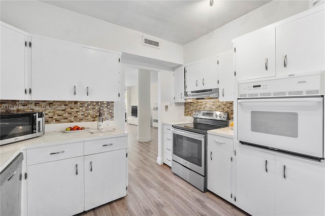 900 Bay Dr Unit 210, Miami Beach, FL 33141 - kitchen with appliances with stainless steel finishes, under cabinet range hood, decorative backsplash, and light wood-type flooring