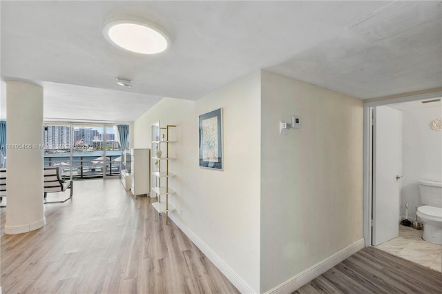 900 Bay Dr Unit 210, Miami Beach, FL 33141 - hallway with light wood-style floors, baseboards, and a wall of windows