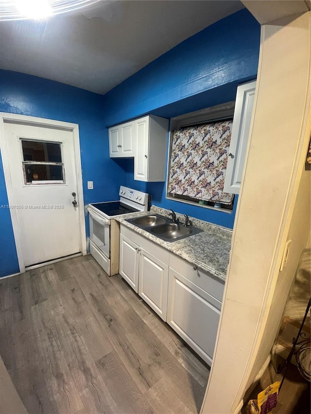 1390 NW 56th St, Miami, FL 33142 - kitchen with electric range, a sink, wood finished floors, and white cabinetry