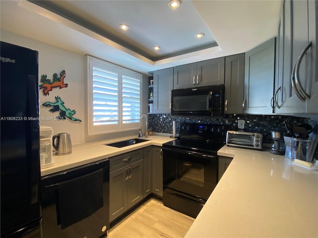 535 Hendricks Isle Unit 303, Fort Lauderdale, FL 33301 - kitchen featuring black appliances, a sink, a raised ceiling, backsplash, and light countertops