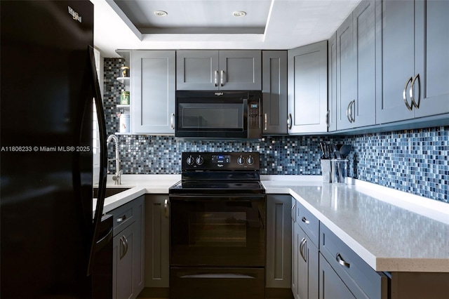 535 Hendricks Isle Unit 303, Fort Lauderdale, FL 33301 - kitchen with black appliances, a raised ceiling, gray cabinetry, and light countertops