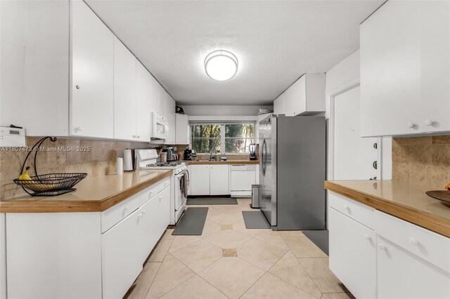 7230 SW 131st Ave, Miami, FL 33183 - kitchen with white appliances, decorative backsplash, a sink, white cabinets, and light tile patterned floors