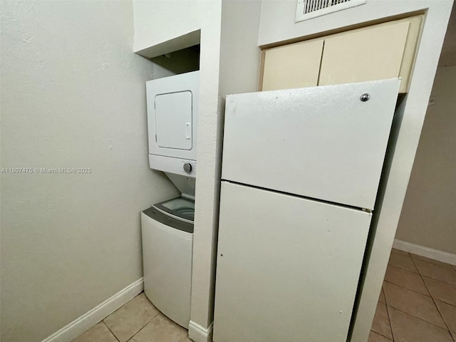2624 Riverside Dr Unit 2624, Coral Springs, FL 33065 - laundry room featuring stacked washer and clothes dryer, light tile patterned floors, and baseboards