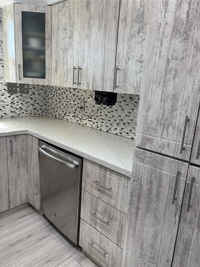 6516 Flagler St, Hollywood, FL 33023 - kitchen with stainless steel dishwasher, backsplash, modern cabinets, light wood finished floors, and glass insert cabinets