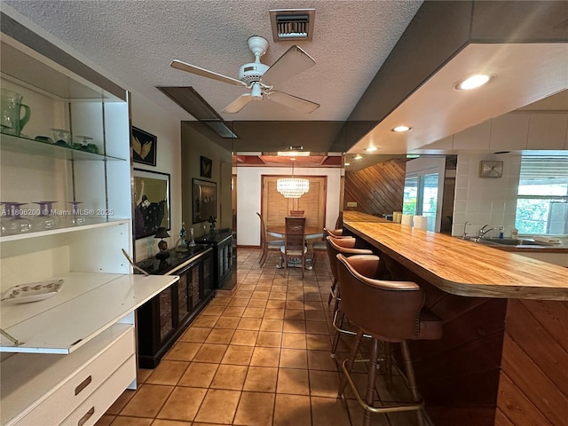2040 N Hibiscus Dr, North Miami, FL 33181 - kitchen featuring light tile patterned flooring, ceiling fan, a textured ceiling, a breakfast bar, and butcher block countertops