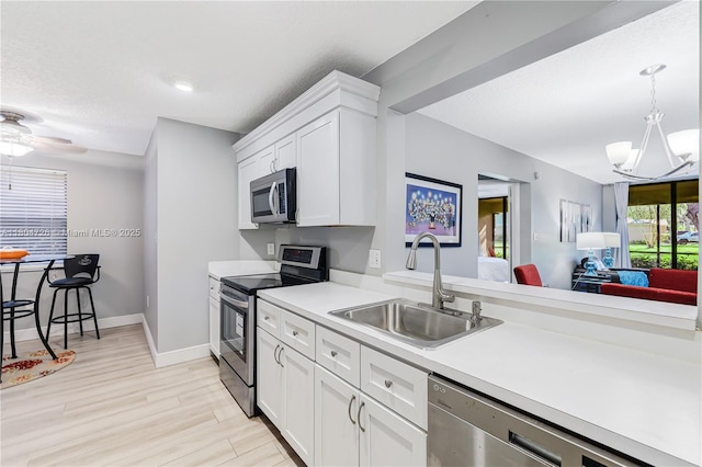 133 NW 98th Ter, Plantation, FL 33324 - kitchen with appliances with stainless steel finishes, a sink, light countertops, a chandelier, and white cabinets