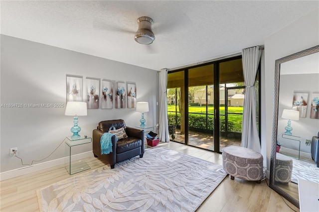 133 NW 98th Ter, Plantation, FL 33324 - living area with wood finished floors, a wall of windows, a textured ceiling, and baseboards