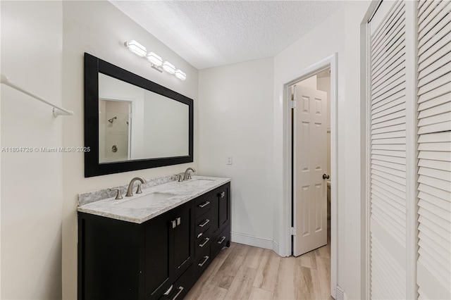 133 NW 98th Ter, Plantation, FL 33324 - full bath featuring wood finished floors, a textured ceiling, double vanity, and baseboards