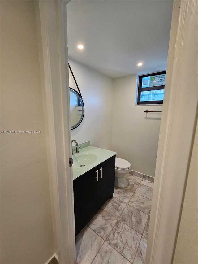 2625 Collins Ave Unit 1408, Miami Beach, FL 33140 - half bathroom with vanity, toilet, baseboards, and marble look tiles