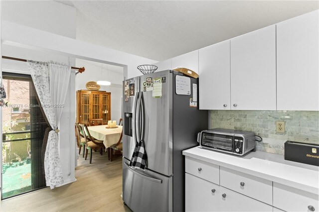 17320 NW 66th Pl, Hialeah, FL 33015 - kitchen with stainless steel fridge, light countertops, light wood finished floors, backsplash, and white cabinets