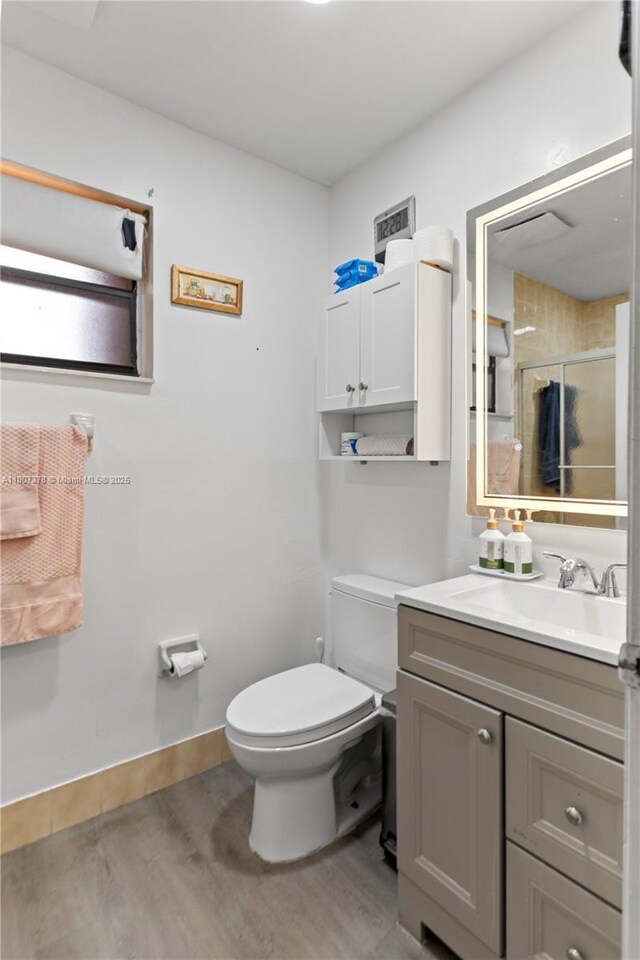 17320 NW 66th Pl, Hialeah, FL 33015 - bathroom featuring wood finished floors, toilet, a shower stall, vanity, and baseboards