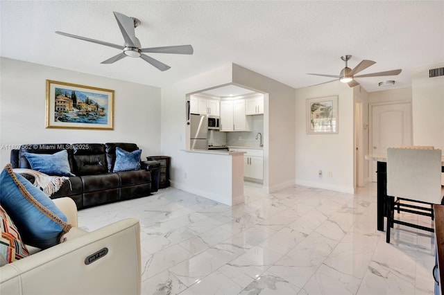 2929 SE Ocean Blvd Unit 123-2, Stuart, FL 34996 - living area featuring ceiling fan, baseboards, a textured ceiling, and light marble finish flooring