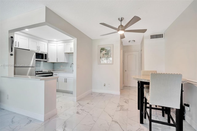 2929 SE Ocean Blvd Unit 123-2, Stuart, FL 34996 - kitchen featuring appliances with stainless steel finishes, a ceiling fan, a sink, light marble finish flooring, and baseboards