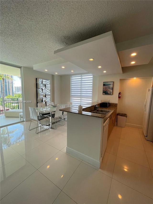 17555 Atlantic Blvd Unit 702, Sunny Isles Beach, FL 33160 - kitchen featuring white appliances, dark countertops, a textured ceiling, a sink, and light tile patterned floors