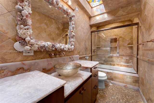 5725 N Bayshore Dr, Miami, FL 33137 - bathroom featuring vanity, tiled shower / bath, toilet, tile walls, and a skylight
