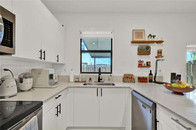 12982 SW 232nd Ln, Miami, FL 33170 - kitchen with a sink, stainless steel appliances, open shelves, white cabinets, and light stone countertops