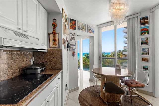 8925 Collins Ave Unit 4A, Surfside, FL 33154 - kitchen featuring black electric stovetop, a chandelier, tasteful backsplash, and healthy amount of natural light