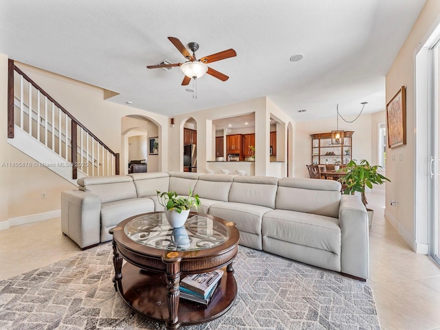 19165 N Gardenia Ave, Weston, FL 33332 - living room featuring a ceiling fan, stairway, baseboards, light tile patterned floors, and arched walkways