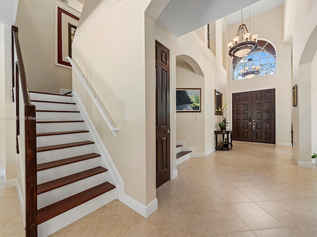 19165 N Gardenia Ave, Weston, FL 33332 - tiled entryway with stairs, a chandelier, arched walkways, a towering ceiling, and baseboards