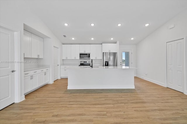 520 SW 28th St, Cape Coral, FL 33914 - kitchen featuring appliances with stainless steel finishes, vaulted ceiling, a center island with sink, light countertops, and white cabinetry
