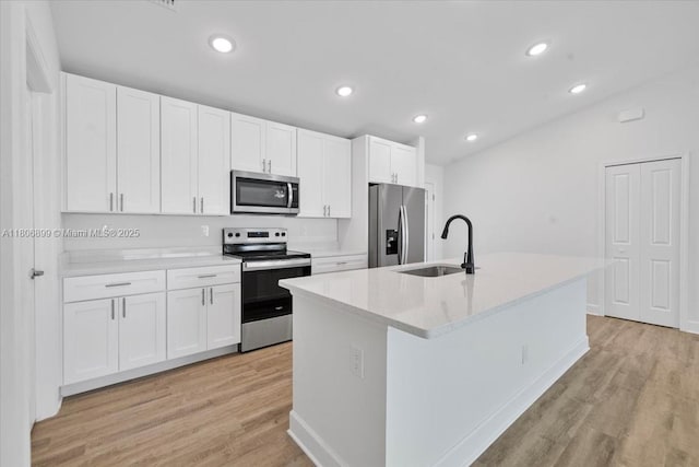 520 SW 28th St, Cape Coral, FL 33914 - kitchen featuring appliances with stainless steel finishes, light wood-style flooring, white cabinetry, an island with sink, and recessed lighting