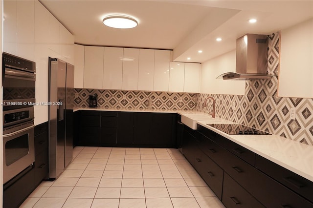 500 Three Islands Blvd Unit 106, Hallandale Beach, FL 33009 - kitchen with wall chimney exhaust hood, appliances with stainless steel finishes, modern cabinets, white cabinetry, and tasteful backsplash