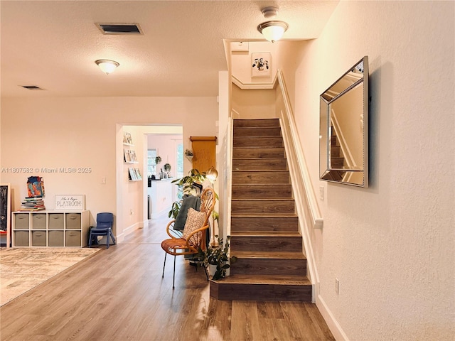 12154 SW 27th St Unit 1102, Miramar, FL 33025 - staircase with wood finished floors, a textured ceiling, baseboards, and a textured wall