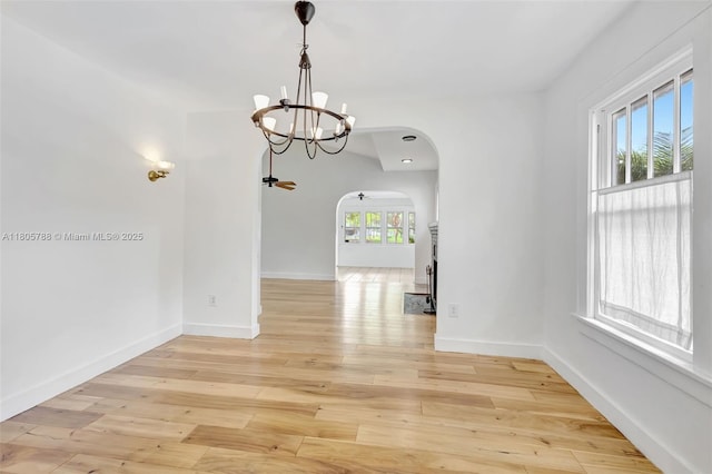 1031 SW 4th St, Fort Lauderdale, FL 33312 - unfurnished dining area with arched walkways, a chandelier, light wood-type flooring, and baseboards