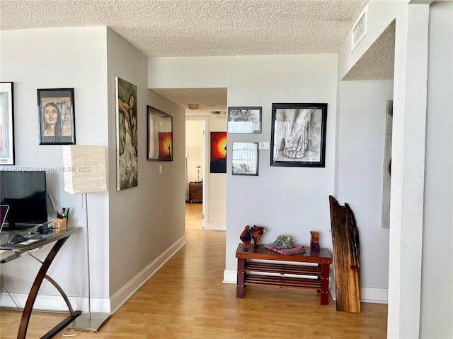 2750 NE 183rd St Unit 2308, Aventura, FL 33160 - hallway with light wood-type flooring, a desk, a textured ceiling, and baseboards