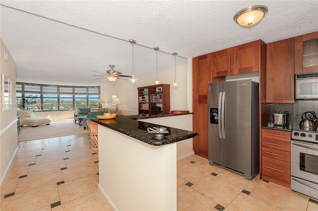3051 NE 48th St Unit 604, Fort Lauderdale, FL 33308 - kitchen featuring stainless steel appliances, light tile patterned floors, open floor plan, a ceiling fan, and brown cabinets