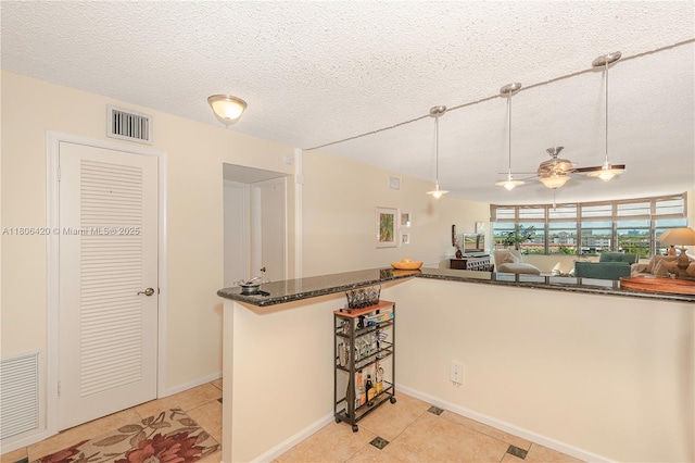 3051 NE 48th St Unit 604, Fort Lauderdale, FL 33308 - kitchen with light tile patterned flooring, a textured ceiling, a ceiling fan, pendant lighting, and dark stone counters