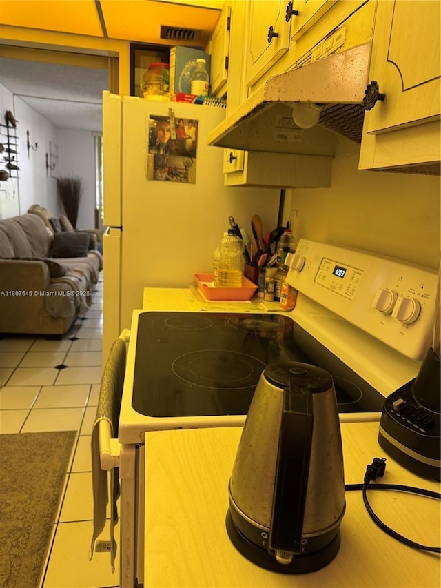 2600 NW 49th Ave Unit 103, Lauderdale Lakes, FL 33313 - kitchen with white range with electric cooktop, light tile patterned floors, open floor plan, light countertops, and under cabinet range hood