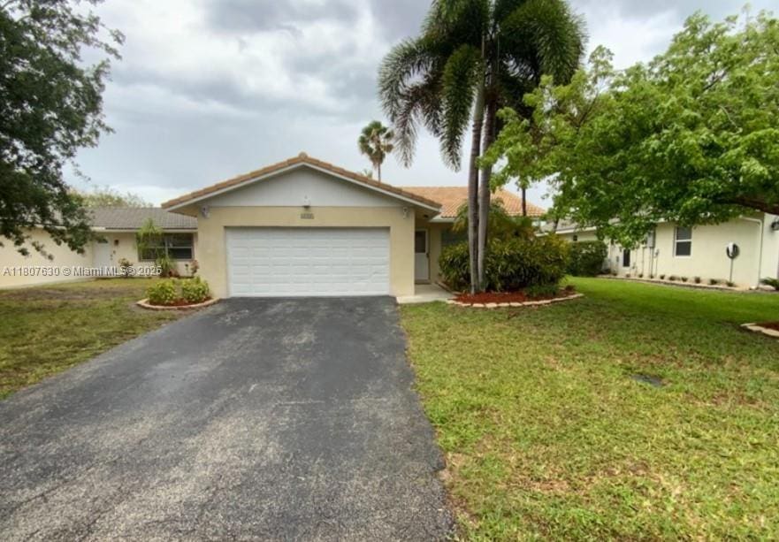 2731 NW 123rd Ave, Coral Springs, FL 33065 - ranch-style home with asphalt driveway, a garage, stucco siding, and a front lawn