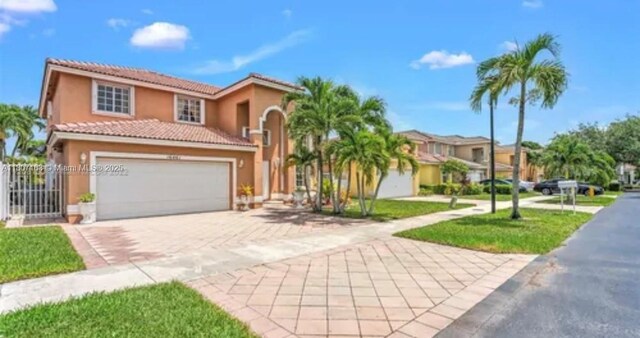 16461 SW 100th Ter, Miami, FL 33196 - mediterranean / spanish-style home with decorative driveway, stucco siding, a tile roof, and an attached garage